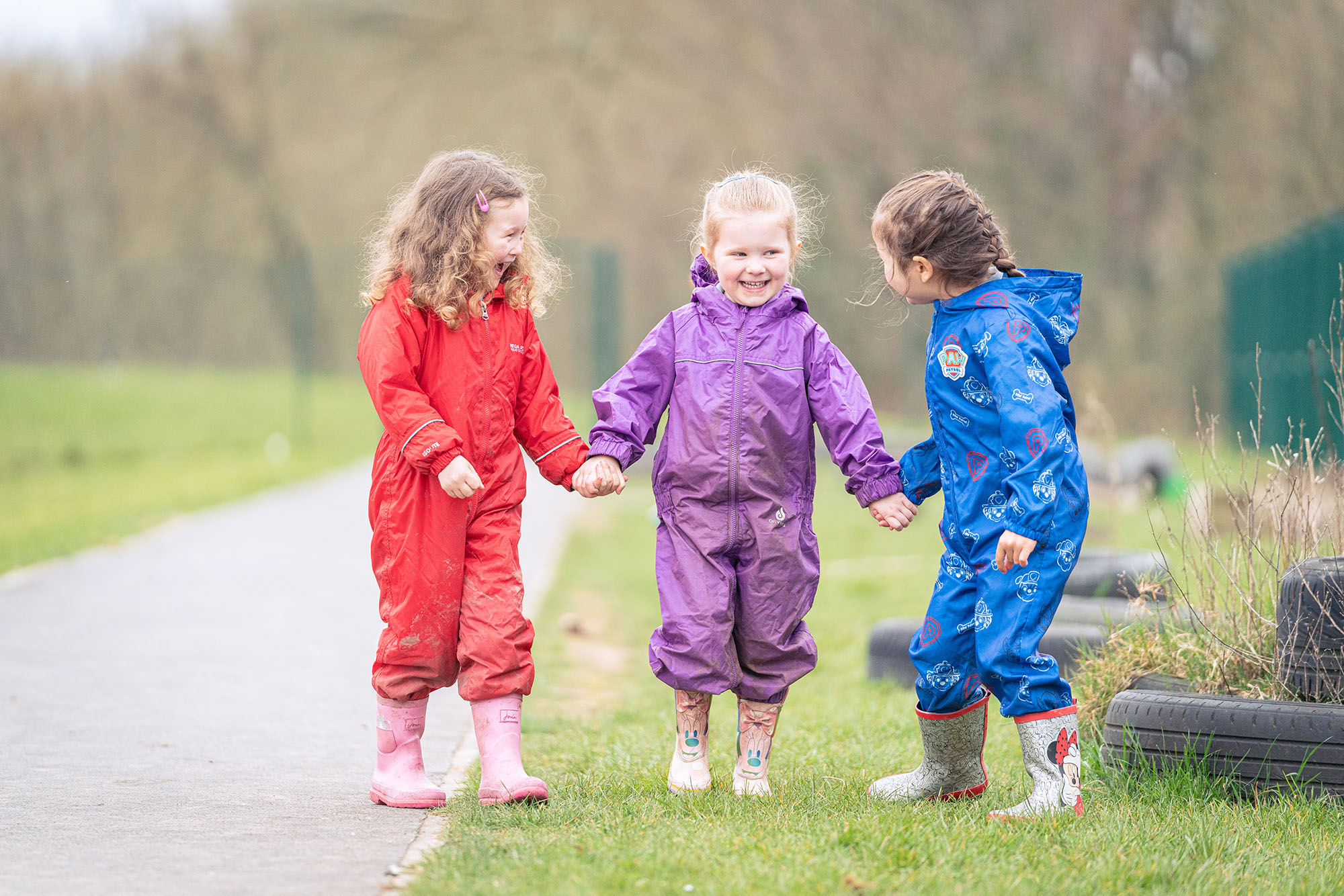 three pupils are dressed in waterproof outfits as they get ready for Forest school at Cheadle Hulme Primary School.