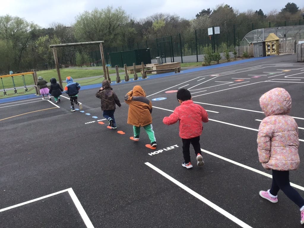 Children from Pre-School walk in a line on the new playground markings