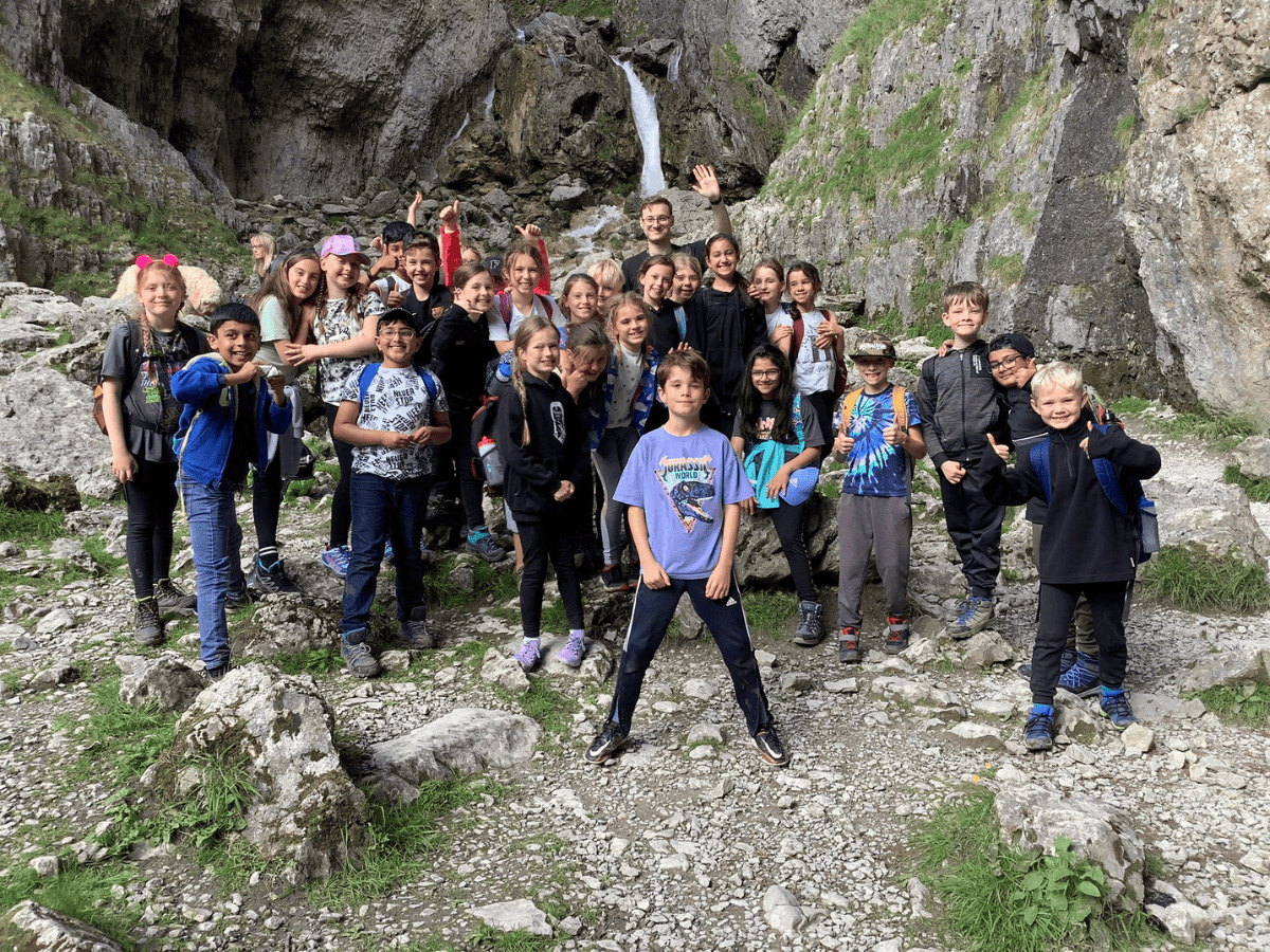 Cheadle Hulme Primary School pupils from Year 4 stand in front of a scenic trail in Malham.