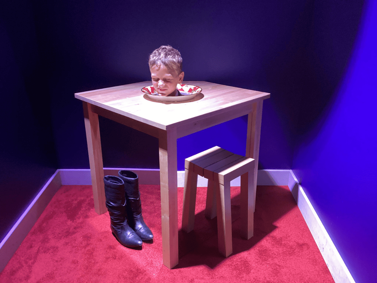 A pupil from Cheadle Hulme Primary School interacts with an illusion at the Science and Industry Museum in Manchester. It appears as though his head is on a plate on a table due to mirrors hiding his body.